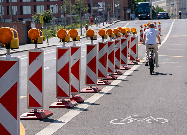 Germany, Berlin, Central Berlin, June 15, 2025 - Rear view of a cyclist on a cycle path bordered by traffic beacons in a row,  on a city street