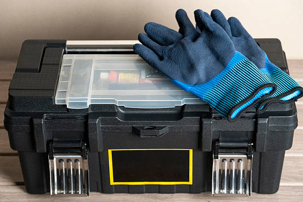 Protective blue work gloves placed on a black plastic toolbox with transparent compartments. Ideal image for construction, DIY, home improvement, and tool safety themes