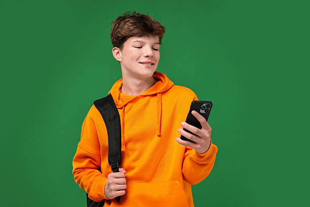 istock Teenage boy with smartphone and backpack on green background 2223204824