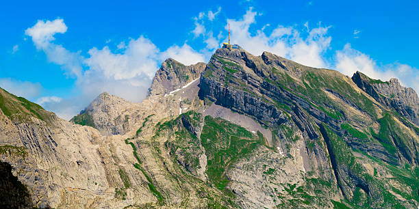 Towering mountain landscape features rocky formations and lush greenery under a bright blue sky. Stunning natural beauty attracts hikers and nature lovers in summer.