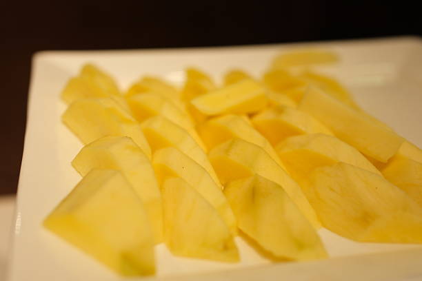istock Ripe yellow mango flesh, cut into jagged slices, placed on a white plate against a multicolored background 2223211033