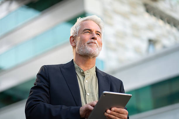 istock Senior businessman using tablet outside modern office building 2223213353