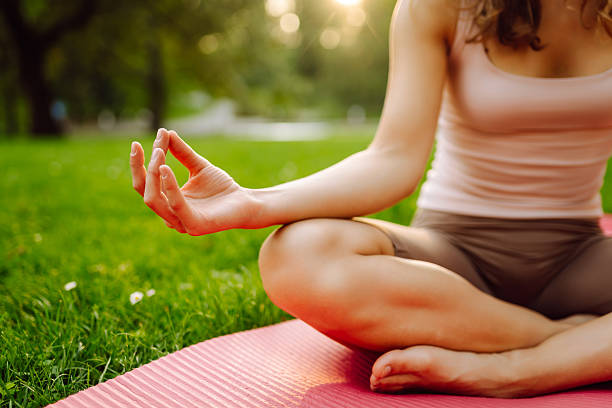 istock Young woman meditating on mat in sunny park. 2223215961