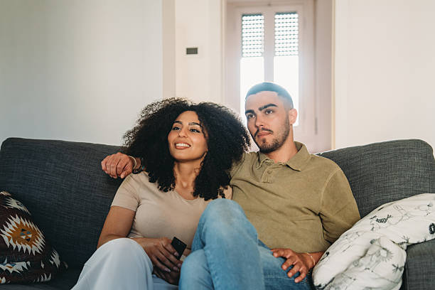istock Young couple relaxing on sofa watching television at home 2223218231