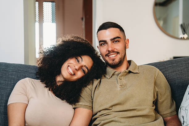 istock Happy couple relaxing on sofa at home smiling at camera 2223218236
