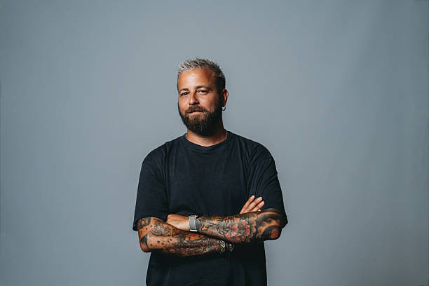 istock Serious tattooed man with crossed arms looking at camera 2223218502