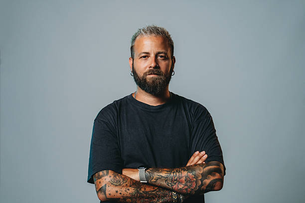 istock Serious man with crossed arms and tattoos looking at camera 2223218503