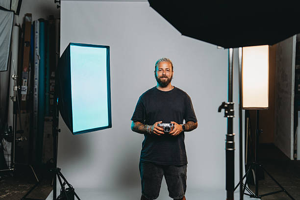 Portrait of a photographer holding a vintage camera in a professional studio with lighting equipment, softboxes and backdrop