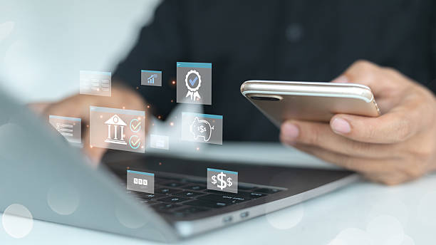 istock A man using a smartphone and laptop with floating digital finance icons, representing mobile banking and fintech applications. 2223218662