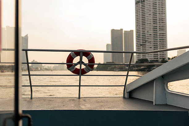 Cityscape view from ship deck, no people, shimmering water, golden hour sunset. Chao Phraya river in Bangkok, Thailand.