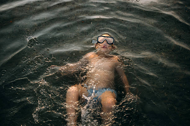 istock Boy with snorkeling goggles floating on back in water 2223222134