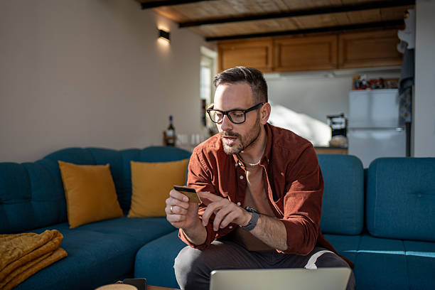 istock Focused man using credit card for online shopping at home 2223222288