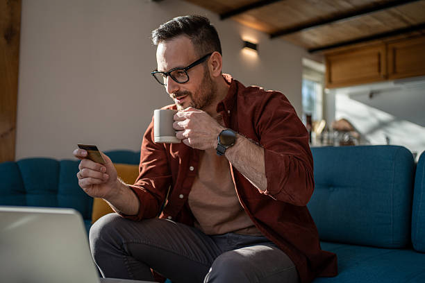 istock Man drinking coffee while shopping online at home 2223222332