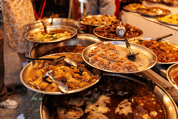 Traditional Thai street food served in metal containers, showcasing a vibrant variety of colorful dishes. The assortment highlights the rich flavors and diverse ingredients typical of Thailand’s bustling street food culture.