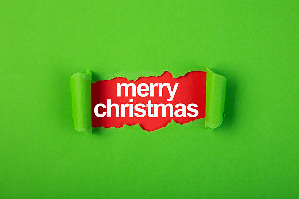 istock Merry christmas revealed under torn green paper on red background 2223225377