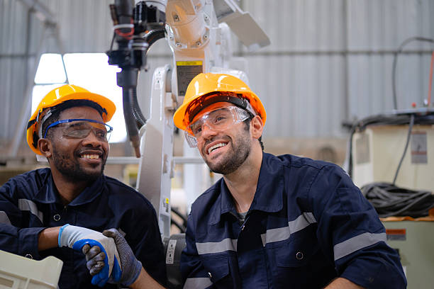 istock Blue collar workers at machine shop with welding robot arm. 2223225579