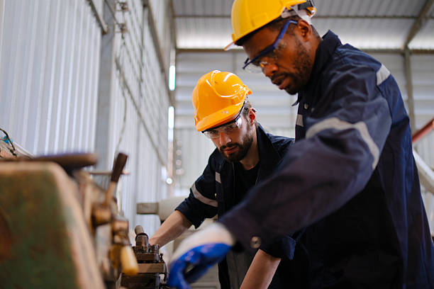 istock Blue collar workers at machine shop with welding robot arm. 2223225619