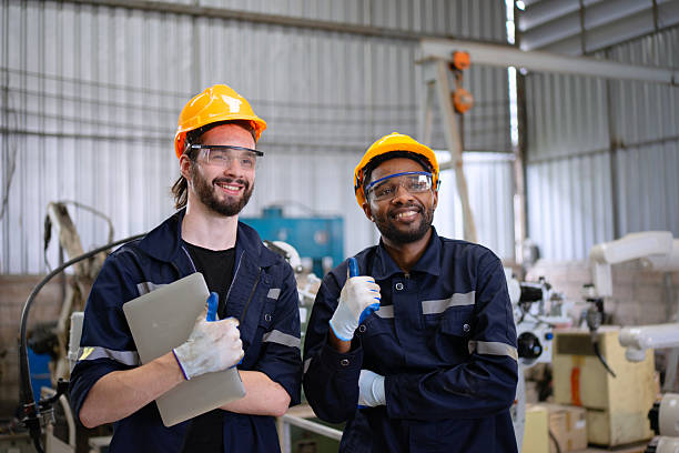 istock Blue collar workers at machine shop with welding robot arm. 2223225661