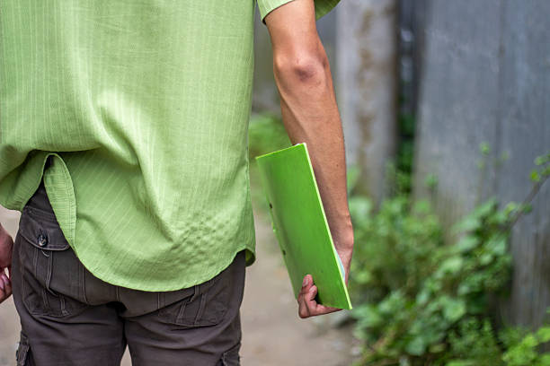 A young man is holding the book and background bur