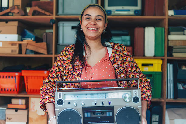 portrait of young smiling woman holding retro tape recorder in hands, smiling to camera