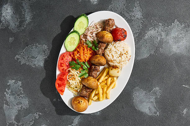 istock Lamb kebab with mushrooms, fries, rice, and fresh vegetables, bright lighting, overhead composition 2223231993