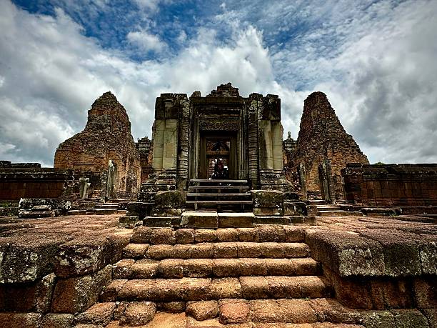 Siem Reap, Siem Reap, Cambodia- July 25, 2023: A grand temple entrance with towering structures stands under a dramatic sky, showcasing intricate carvings and weathered stone.