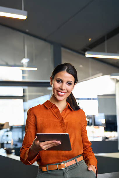 istock Vertical portrait of smiling hispanic young woman using pad tab computer for business. Executive CEO businesswoman saleswoman holding digital tablet pc device for work in office, looking at camera 2223235833
