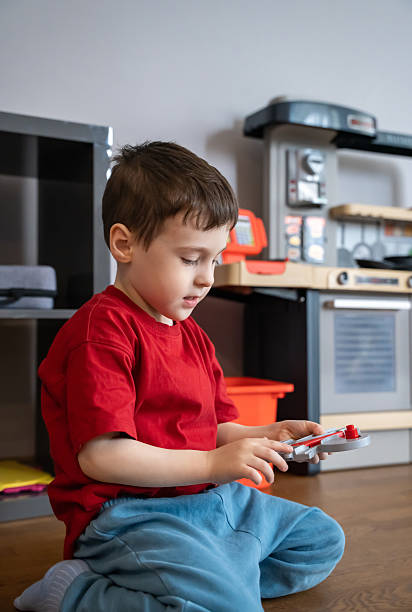 Little boy playing with toys while sitting on the floor at home. Early development, imagination, and childhood learning in a family environment. Child psychology, home life, and early education themes