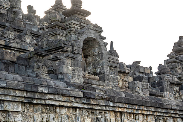 A headless Buddha statue sits in a stone niche on Borobudur temple's ancient upper terrace.