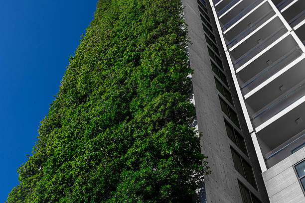 Vertical garden on modern high-rise building against clear blue sky.