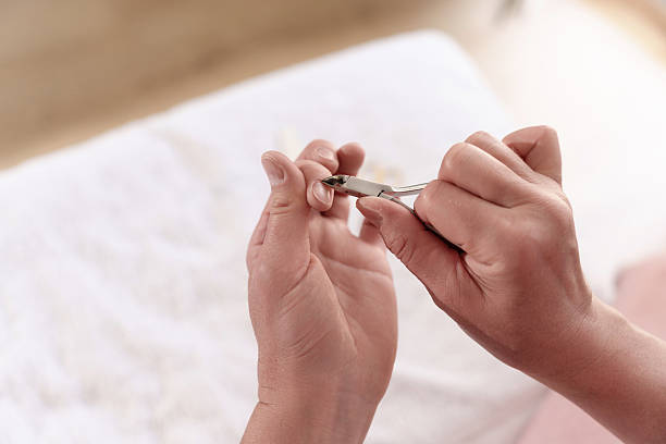 istock Women's hands trimming cuticles using cuticle clippers to maintain healthy and beautiful nails. 2223238671