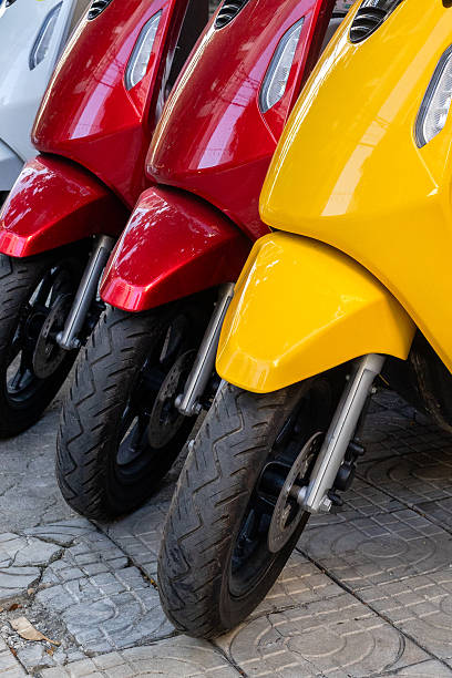 istock Vibrant red, yellow, white scooters lined up on pavement 2223239871