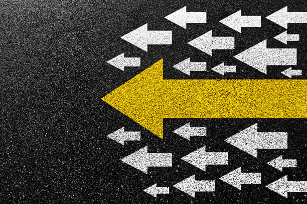 istock Big yellow arrow and small white arrows on asphalt road. Standing out from the crowd. 2223242570