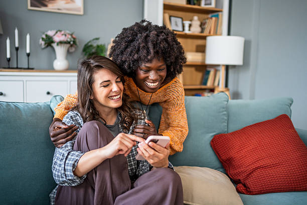istock Two young women sharing a laugh while using a smartphone at home 2223245344