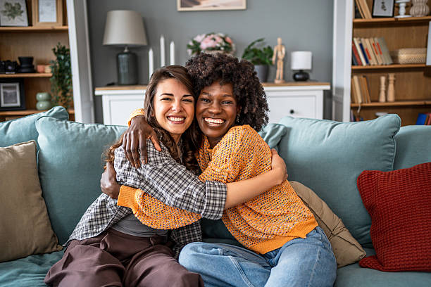istock Two smiling friends embracing on the sofa at home 2223246459