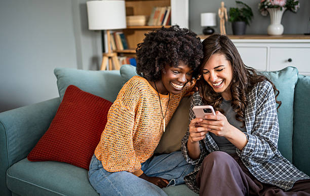 istock Two young women laughing while using a smartphone on the sofa at home 2223246655