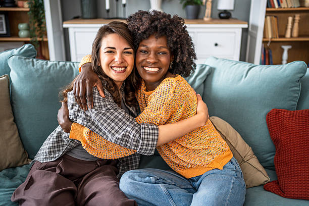 istock Joyful friends embracing on comfortable sofa 2223246911