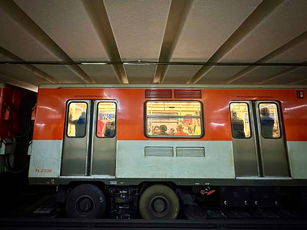 Mexico City, CDMX, Mexico- February 17, 2025: A Mexico City metro train stopped at a platform with passengers inside, framed by the dim underground atmosphere.
