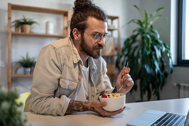 istock Young man working from home and eating a fruit salad 2223250173