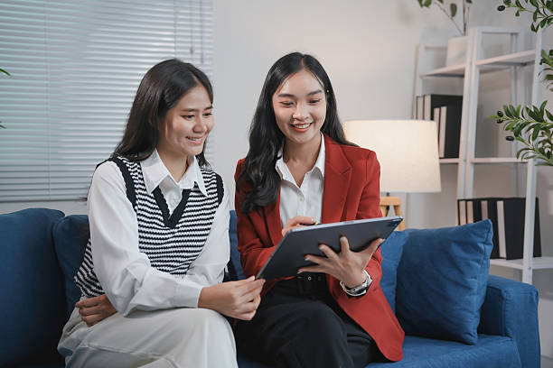 istock Professional women collaborating on digital tablet while sitting on blue office sofa, representing modern workplace interaction and teamwork 2223252382