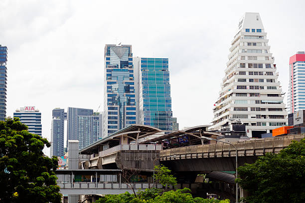 BTS station Chong Nonsi in Bangkok seen from Sathorn Bridge at afternoon. In bottom area are trees along Naradhiwas Rajanagarindra Rd. In background are skyscrapers and office buildings in skyline