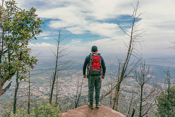 Hiker standing on a mountain top, admiring the stunning view of the valley below
