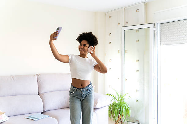istock Woman dancing and taking selfie at home 2223256382