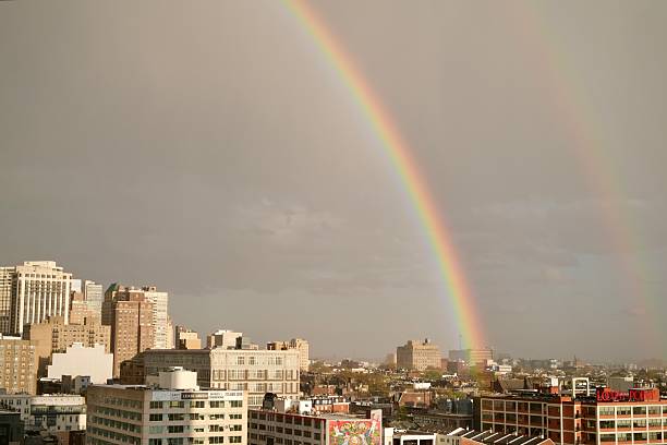 Philadelphia, Pennsylvania, USA- April 15, 2025: A complete double rainbow spans the entire city skyline, emerging after heavy rain and catching sunlight on the horizon.