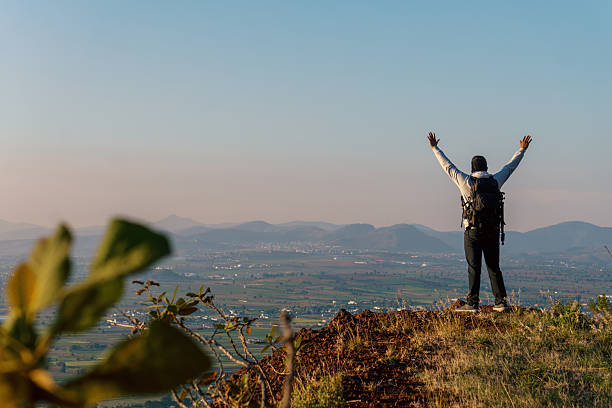 istock a cheering man with open arms on mountain peak cliff 2223259247