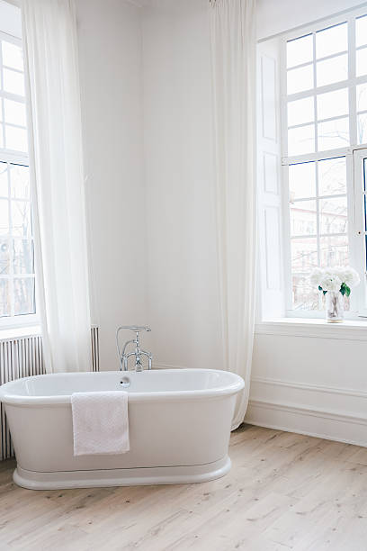 istock Bright and airy bathroom with white bathtub and natural light from large windows 2223263281