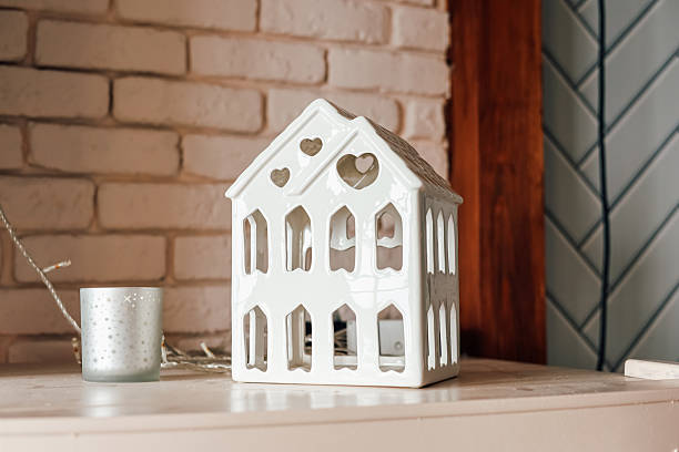 Decorative ceramic house lantern on shelf with warm ambiance in cozy interior setting