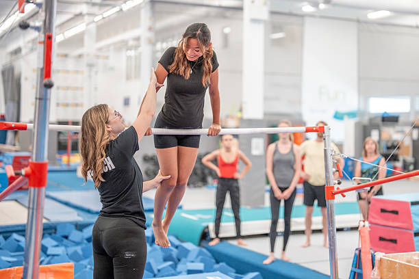 istock Coach Helping Student Practice Gymnastics on Bars in Training Facility 2223263716