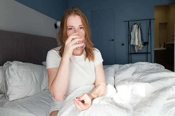 istock Woman Taking Medicine with Water in Bed 2223267659