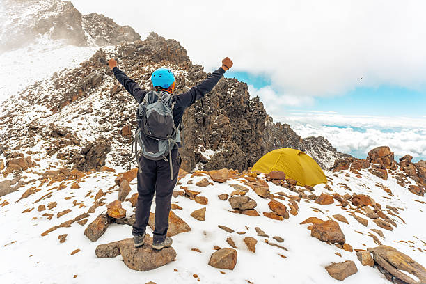Hiker celebrates reaching the summit of iztaccihuatl volcano, with popocatepetl volcano in the background